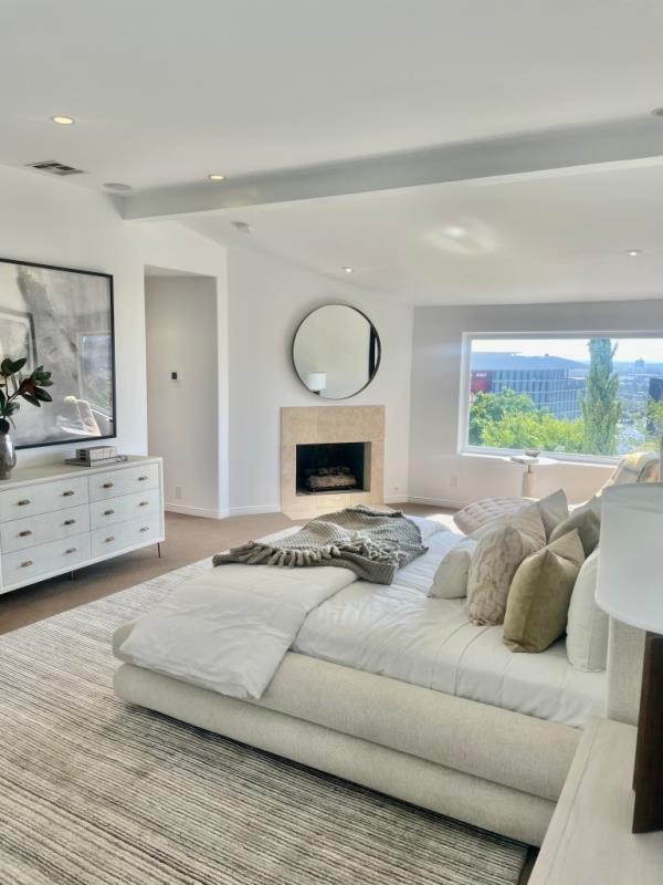 A large bedroom in a Spanish-style home featuring a sizable bed and a fireplace